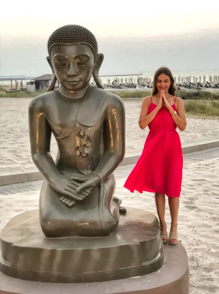 Person standing next to a Buddha statue