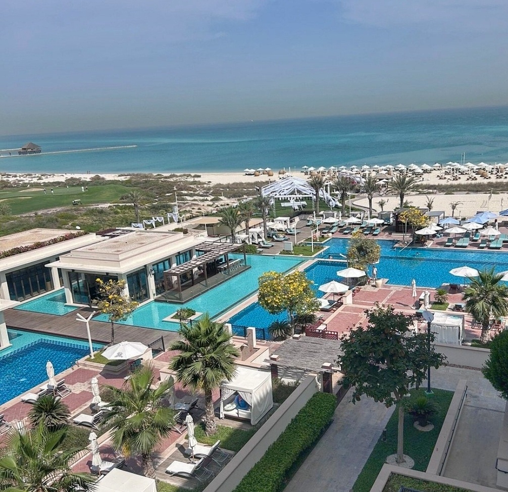 Luxury room view featuring a pool and a beach with vibrant blue water