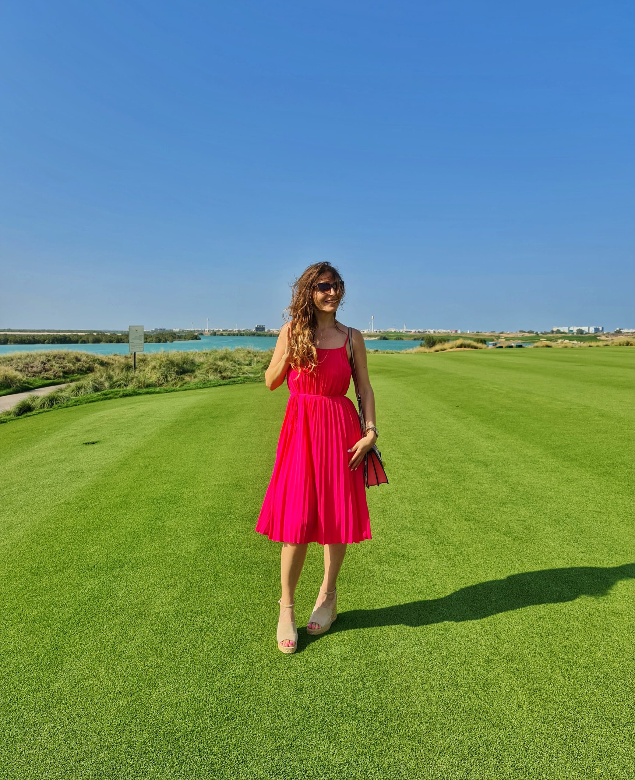 Standing on a golf course with scenic sea views in the background on a sunny day.