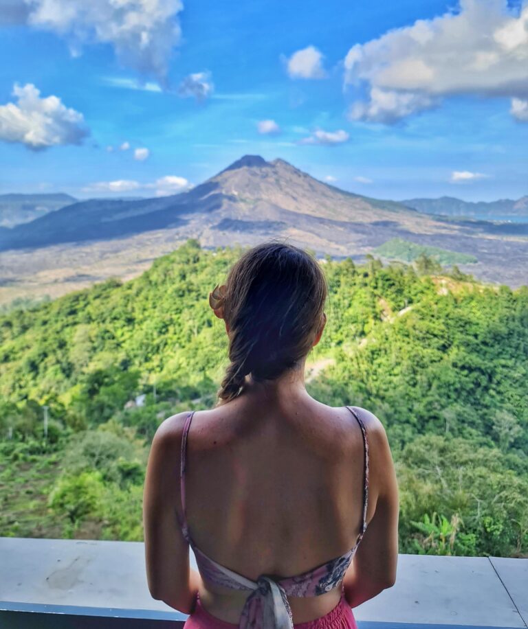 - Active volcano Mount Batur in Bali surrounded by lush greenery and Lake Batur