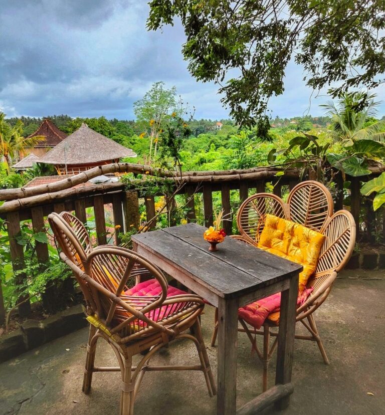 Outdoor seating with a table and two chairs overlooking a beautiful green view in Ubud, surrounded by lush green scenery