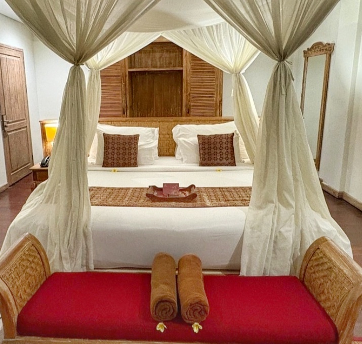 Stylish hotel room in Bali with a neatly arranged bed and mosquito net canopy