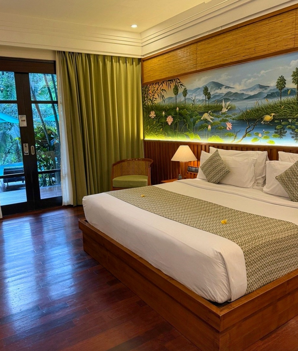 Elegant hotel bedroom in Bali with a decorated wall above the bed and access to a private balcony