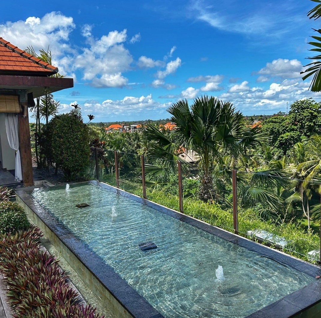 Beautiful swimming pool in Bali on a sunny day with lush greenery