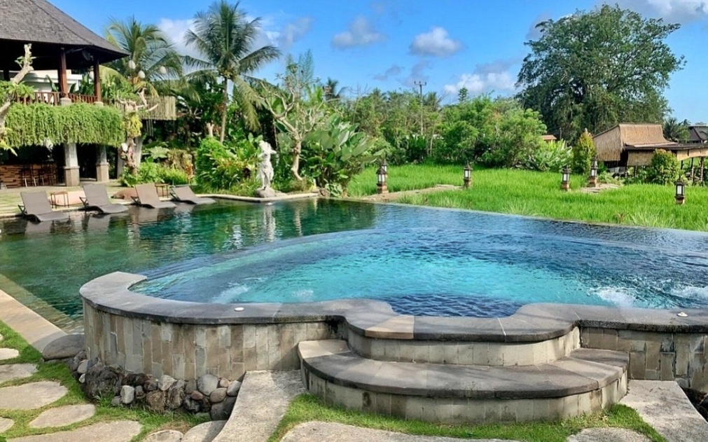 Infinity pool in Bali with a scenic green background and tropical surroundings