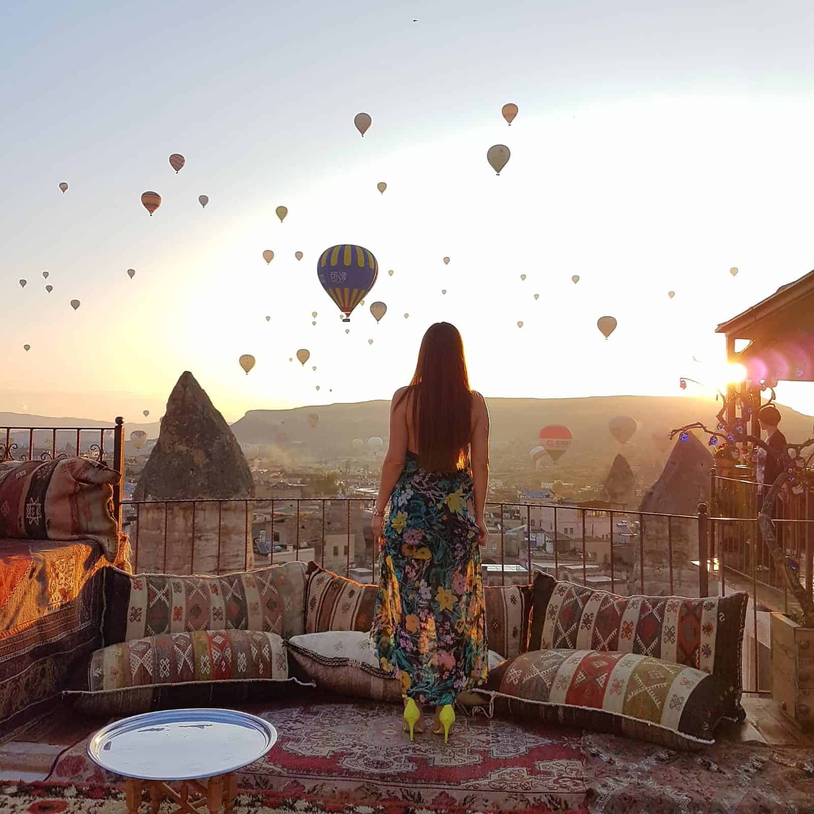 Woman watching hot air balloons at sunrise in Cappadocia, Turkey.