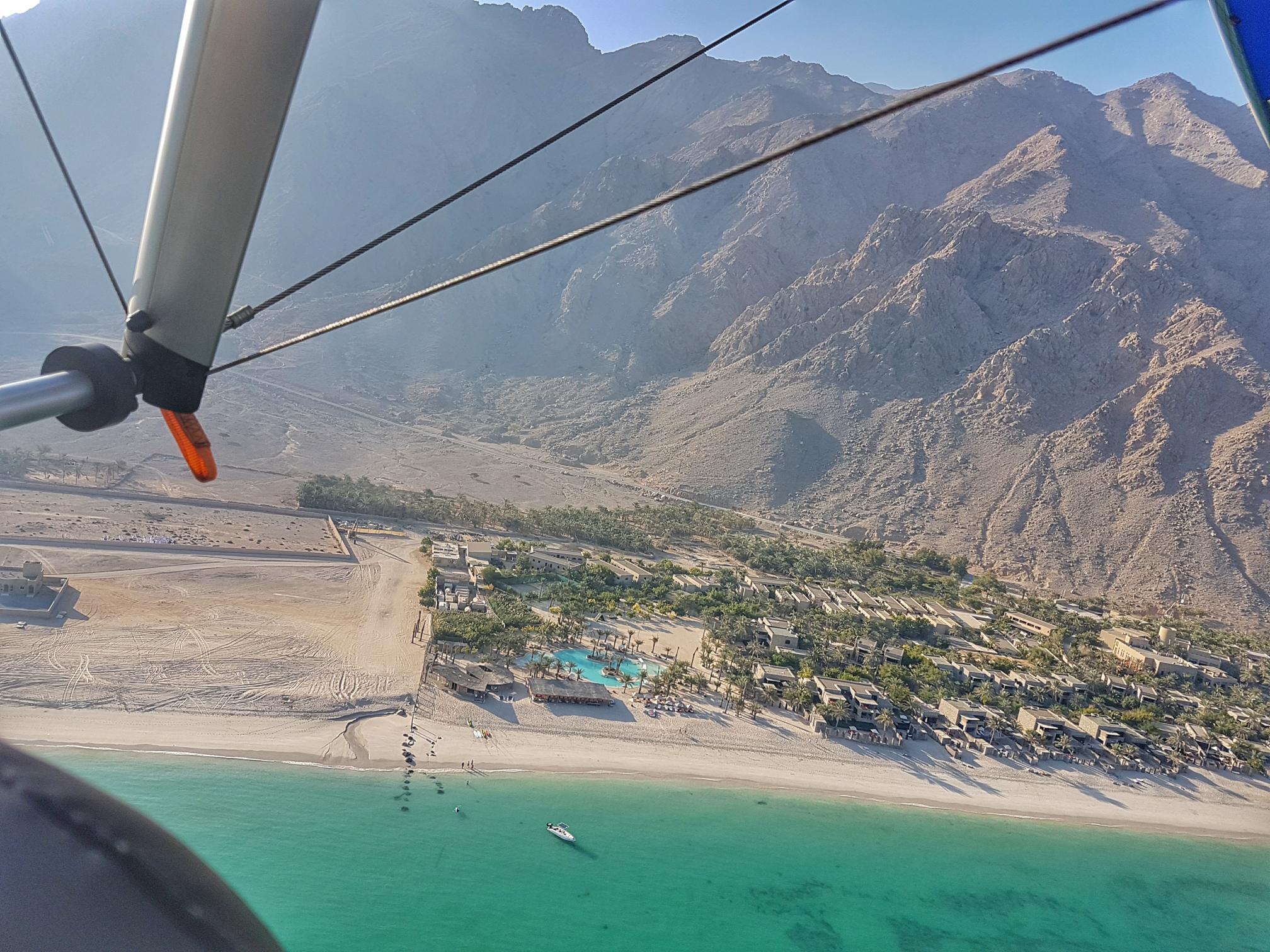 Paragliding over Six Senses Zighy Bay with panoramic views of the resort, mountains, and coastline