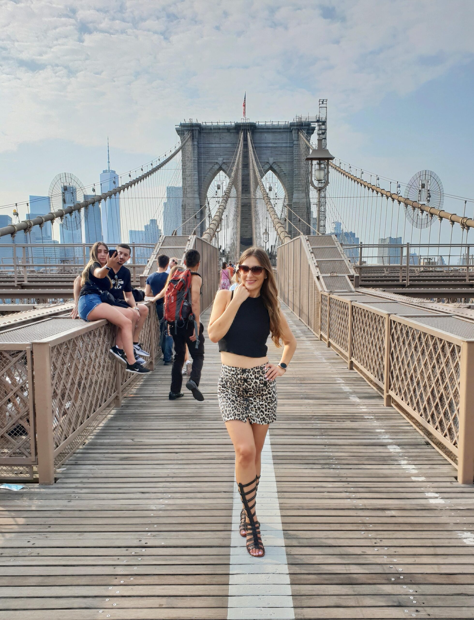 Woman standing on Brooklyn Bridge with New York City skyline in the background