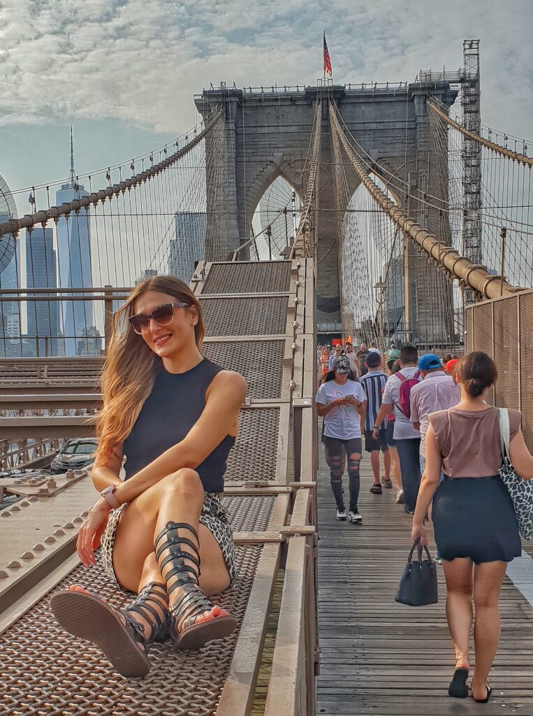 Sitting on the Brooklyn Bridge with Manhattan skyline views in New York City.