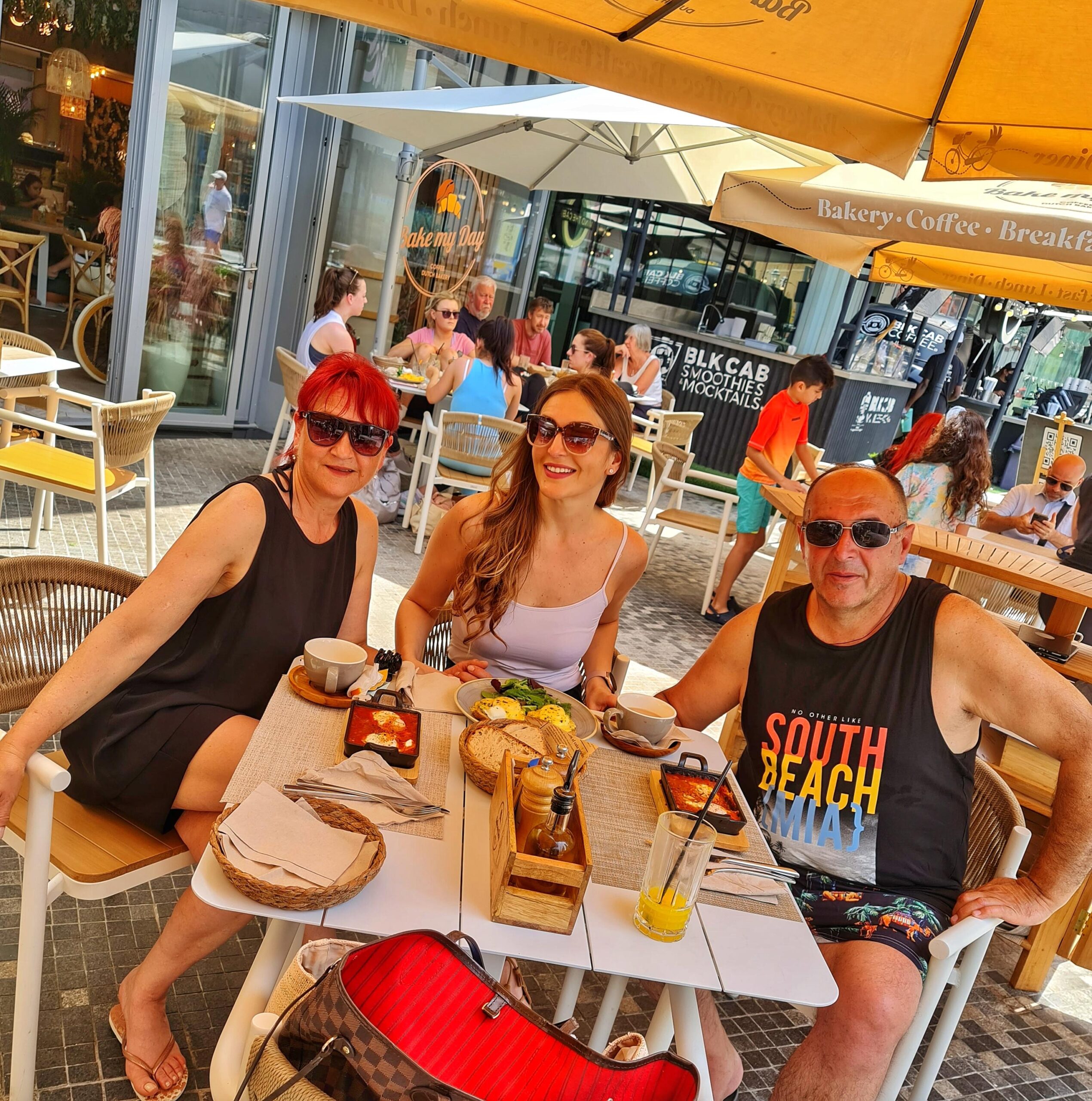 Woman with parents enjoying lunch at JBR near the beach in Dubai