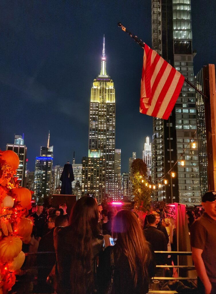 Rooftop bar view of Empire State Building illuminated in the New York City skyline
