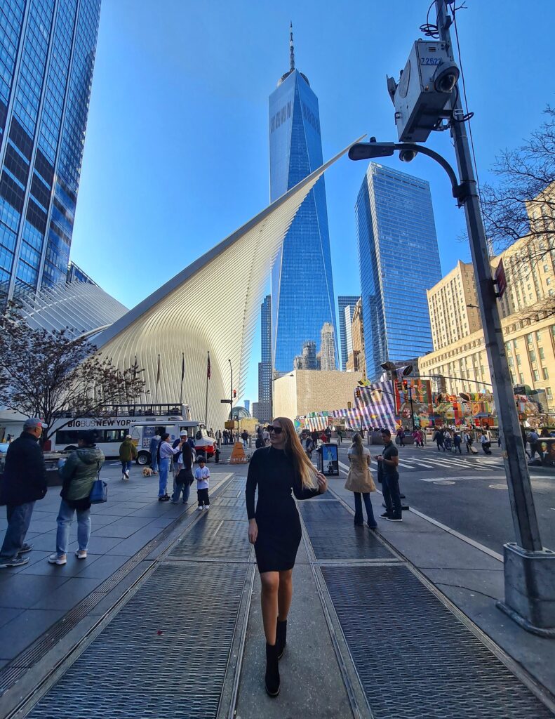 Woman posing near the waterfront with New York skyline and One World Trade Center