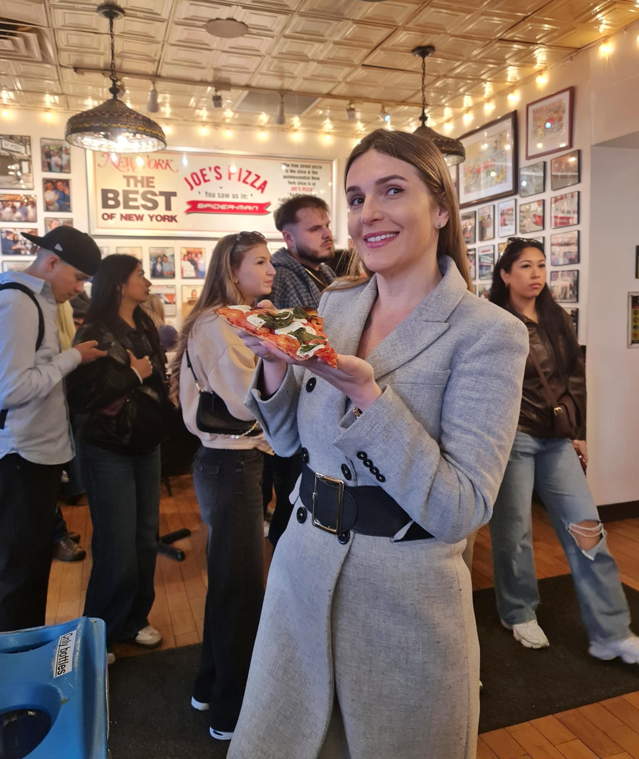 Holding a classic New York pizza slice inside Joe’s Pizza restaurant in New York City.