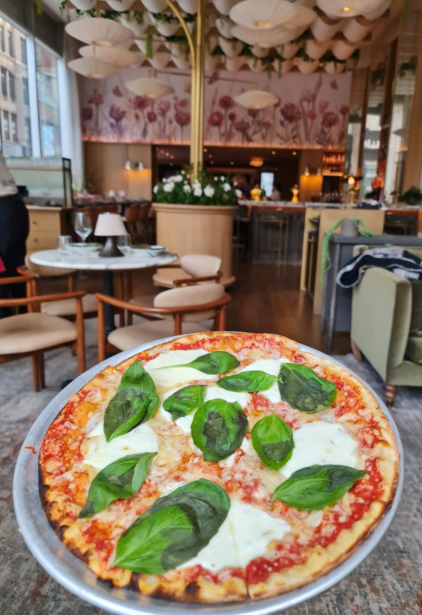 Holding pizza inside Park Rose restaurant with stylish interior in New York City.