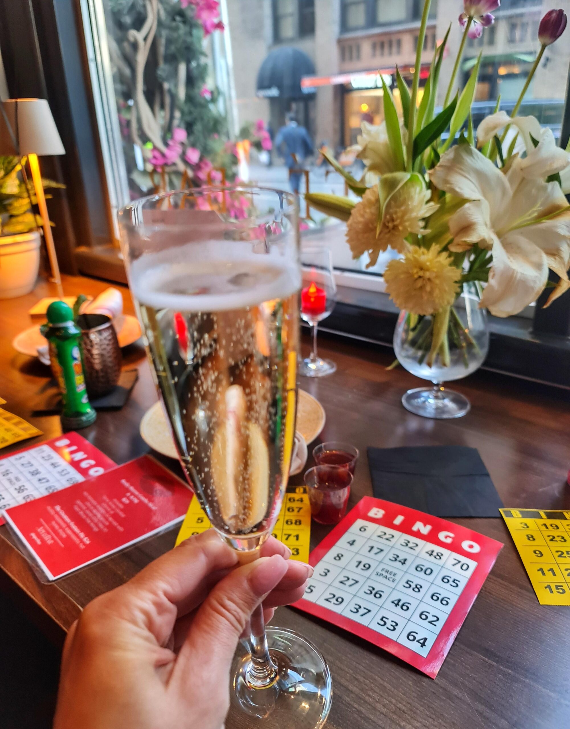 Person holding a glass of prosecco during bingo night at an Italian restaurant in New York City.