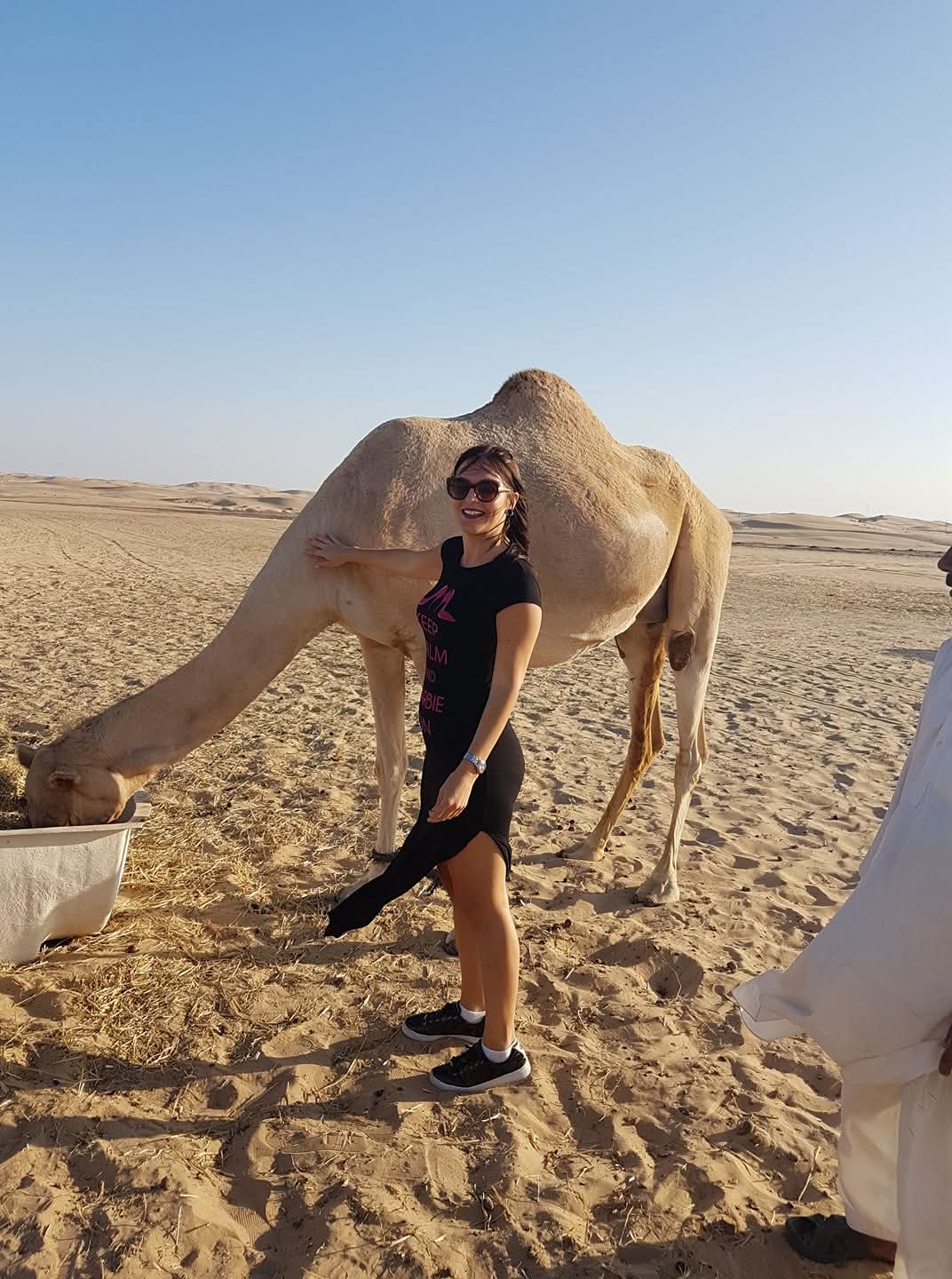 Woman with camel during desert safari in Dubai desert with sand dunes