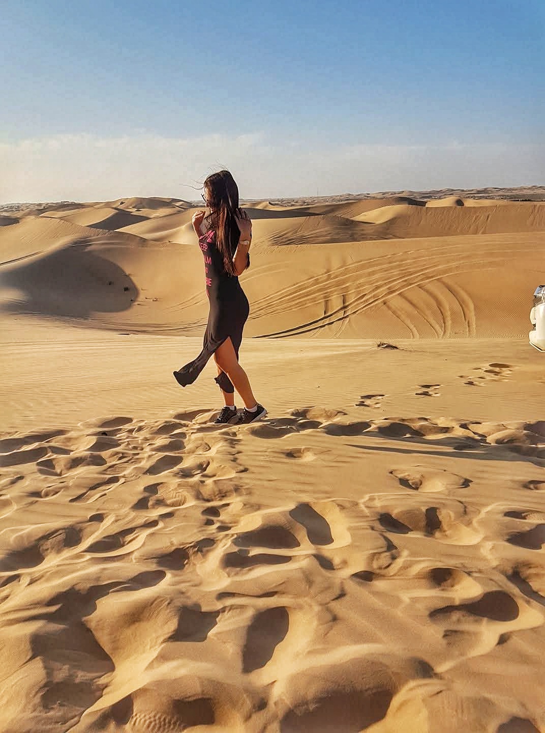 Woman standing in Dubai desert with wide sand dunes and scenic view
