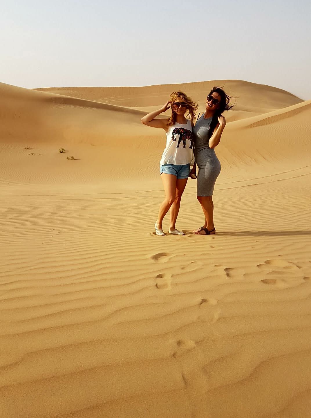 2 women in Dubai desert enjoying golden sand dunes landscape