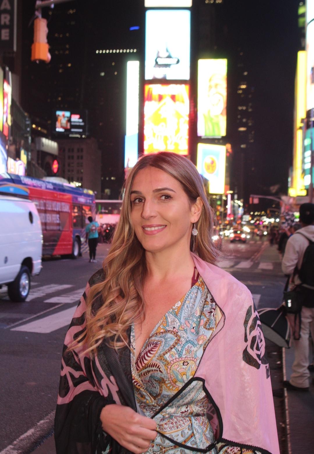 Professional photo of me standing in Times Square with New York City skyline and lights in the background.