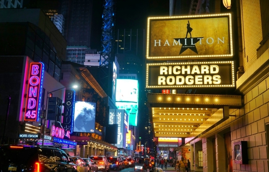 Bright illuminated Broadway Theater District street with theatre marquees at night in New York City