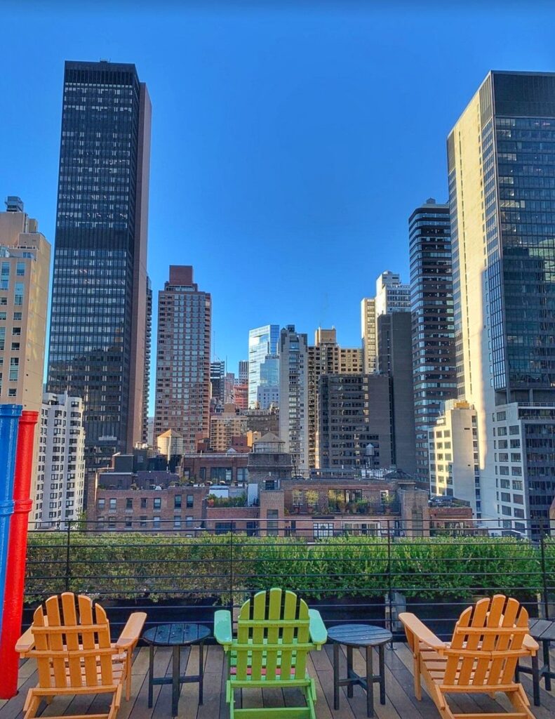 Rooftop view from a hotel with chairs and city skyline in the background.
