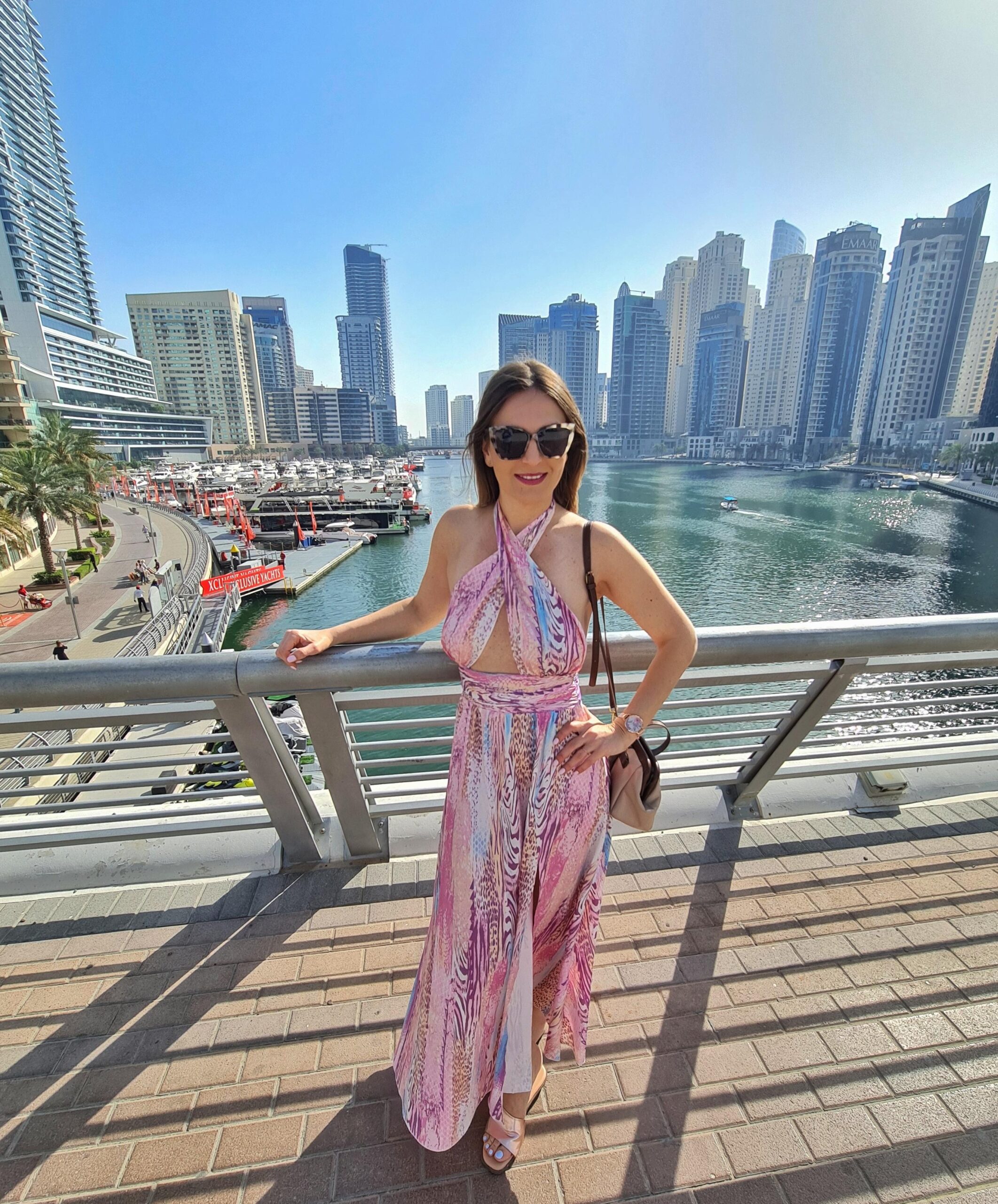 Woman standing on a bridge in Dubai Marina with skyline and water behind