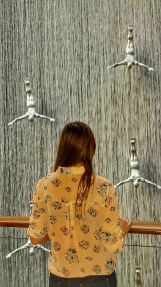 Me inside Dubai Mall with the indoor waterfall and diver sculptures behind